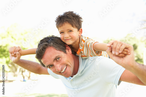 Father Giving Son Ride On Back In Park