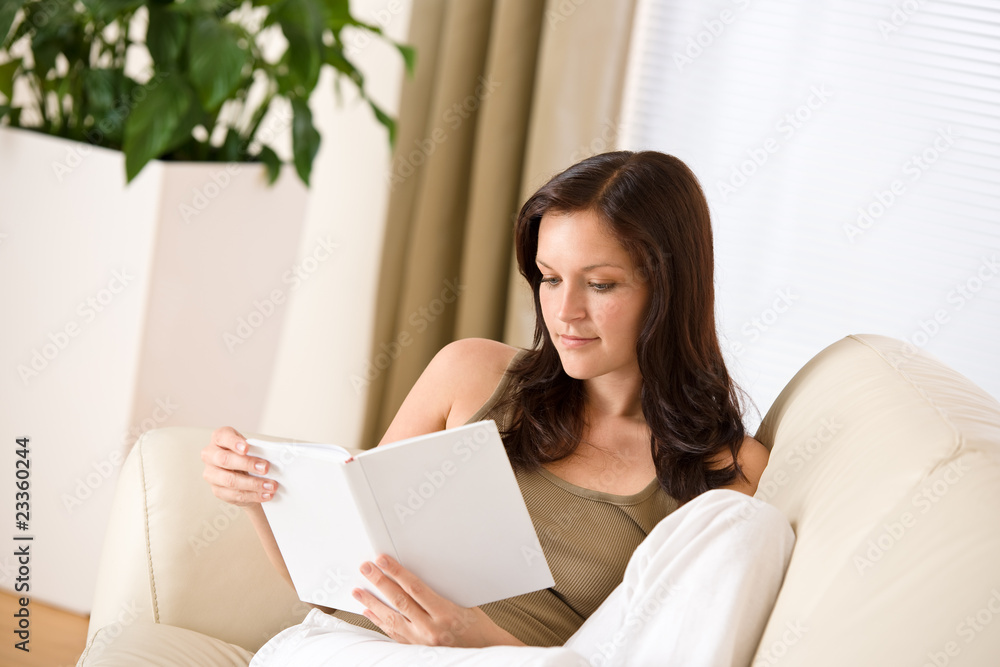Young happy woman read book on sofa Young happy woman read book on sofa