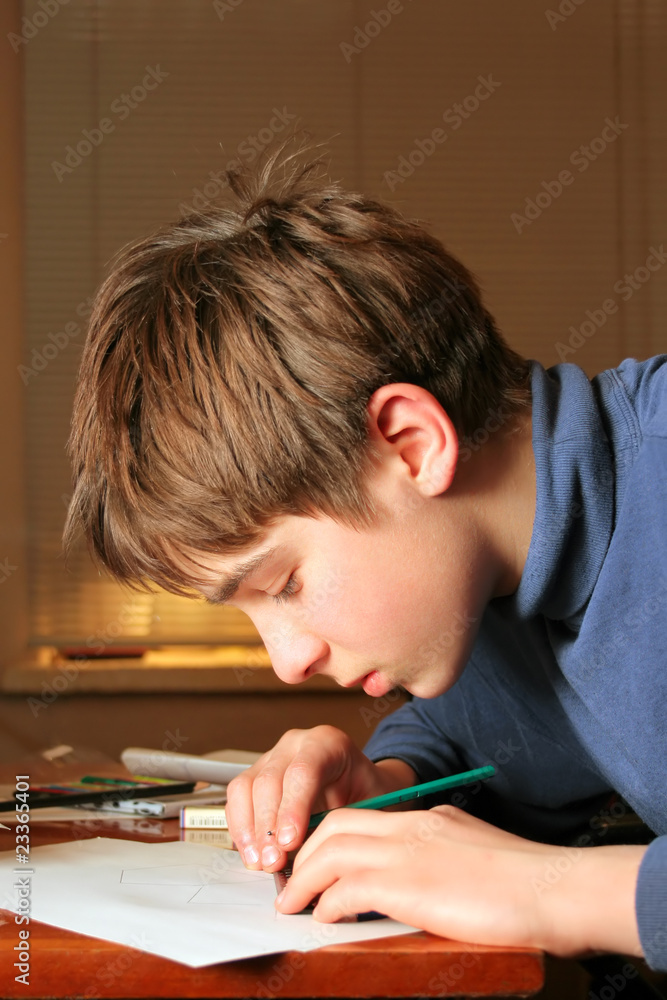 The boy doing lessons and with concentration drawing The boy doing lessons and with concentration drawing