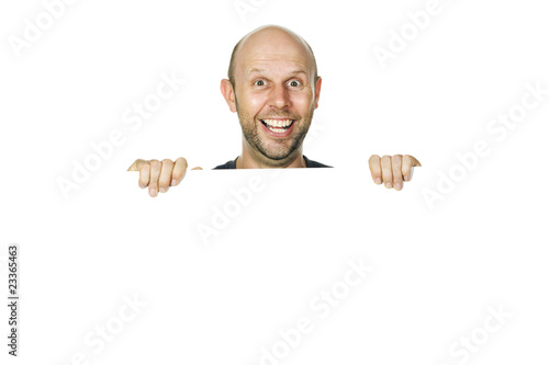 Portrait of a happy funny man peeking over a wall or white sign.