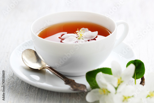 white cup of tea with apple blossoms