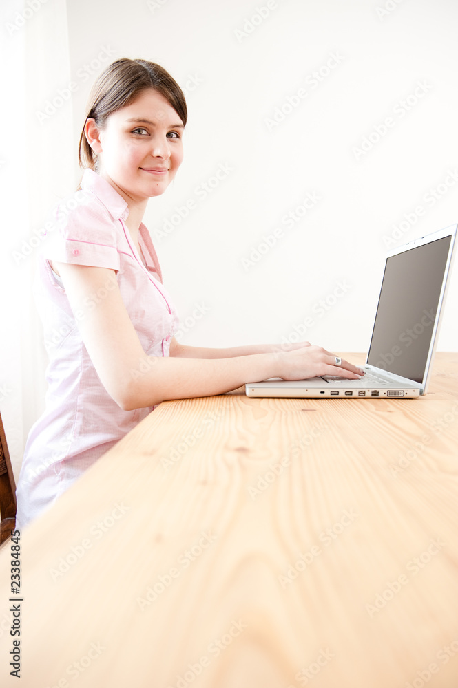 junge frau lächelt und tippt auf laptop an tisch junge frau lächelt und tippt auf laptop an tisch