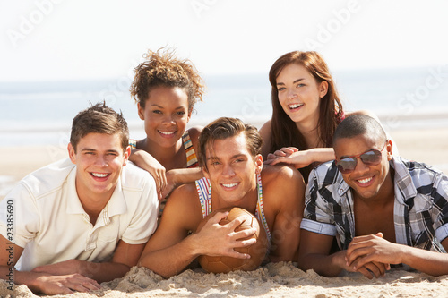 Group Of Friends Relaxing On Beach With Football Together