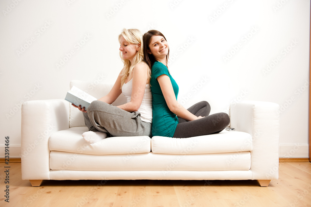 zwei freundinnen entspannen mit buch auf sofa