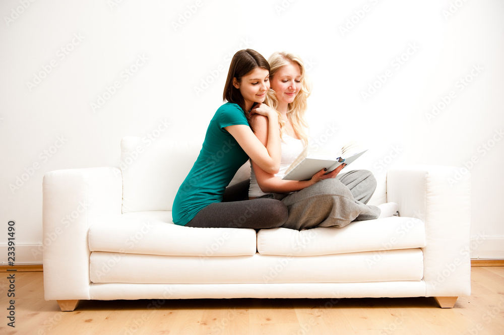 zwei freundinnen entspannen mit buch auf sofa zwei freundinnen entspannen mit buch auf sofa