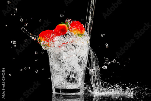 splash in a glass with three red berry and ice on a black backgr