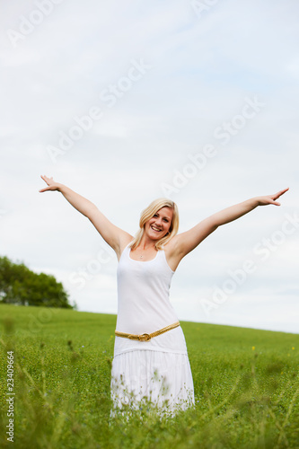 Young woman in field arms outstretched with joy