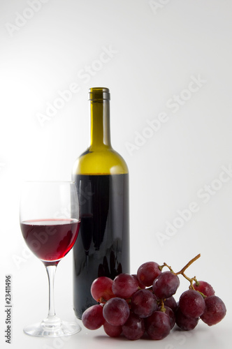 Un bicchiere di vino, grappolo e bottiglia