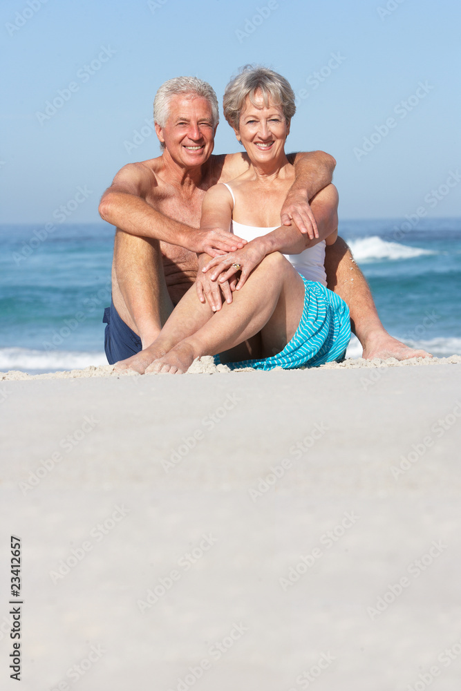 Senior Couple On Holiday Sitting On Sandy Beach Senior Couple On Holiday Sitting On Sandy Beach