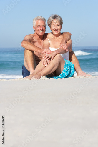 Senior Couple On Holiday Sitting On Sandy Beach