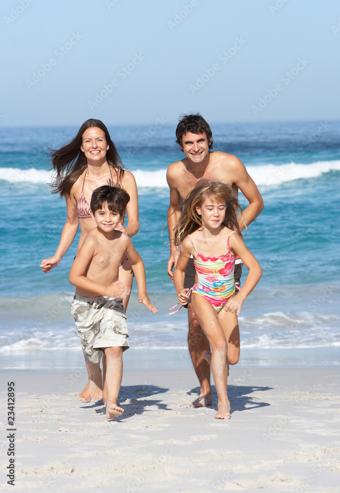 Young Family Running Along Beach on Holiday Young Family Running Along Beach on Holiday