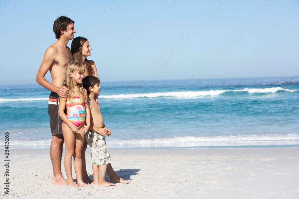 Young Family Standing On Sandy Beach on Holiday