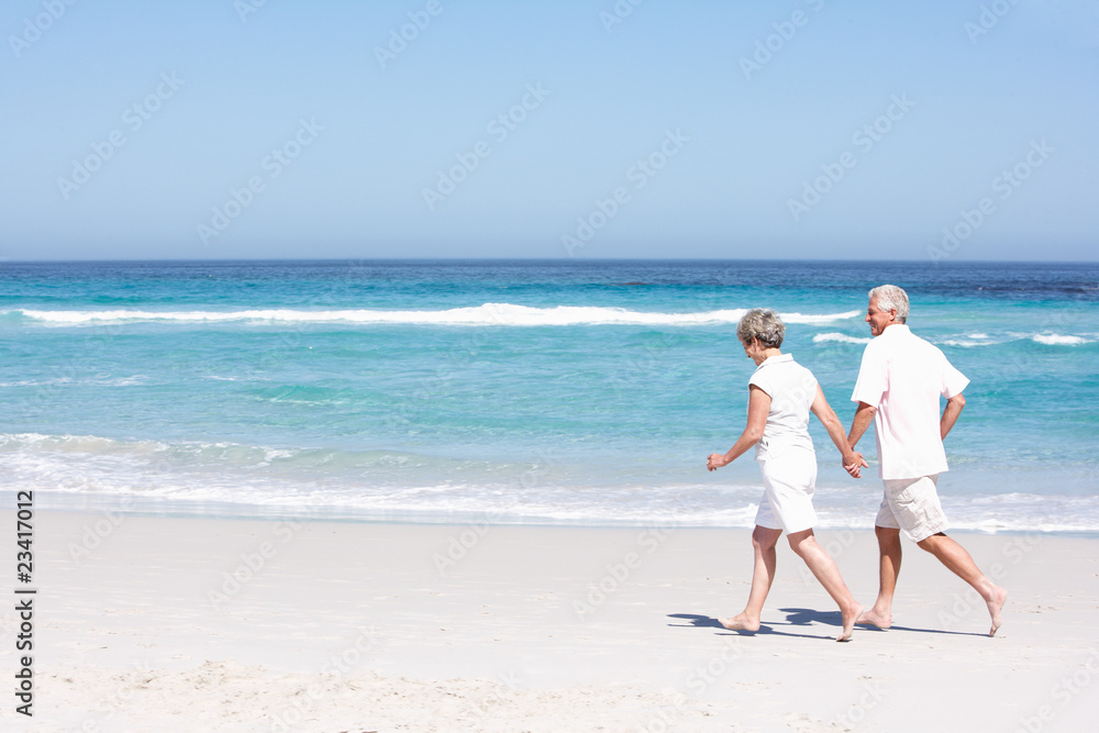 Senior Couple On Holiday Running Along Sandy Beach Senior Couple On Holiday Running Along Sandy Beach