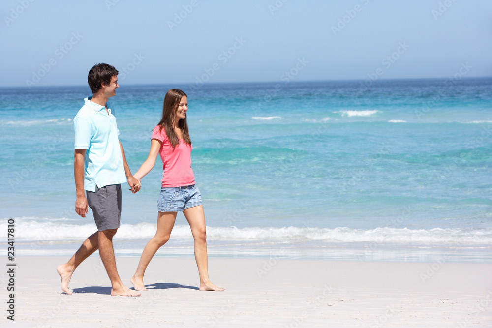 Couple On Holiday Walking Along Sandy Beach Couple On Holiday Walking Along Sandy Beach