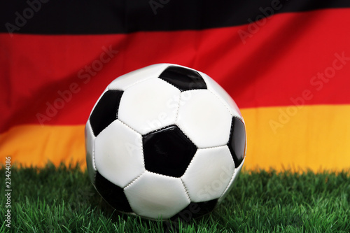 Fu  ball auf Rasen vor Deutschlandfahne