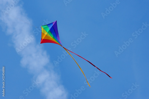 colorful kite flying below an aircraft vapor trail