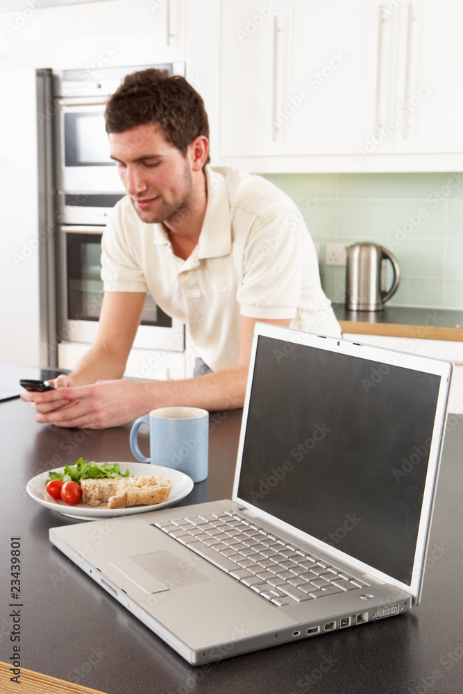 Young Man With Laptop In Modern Kitchen About To Eat Meal