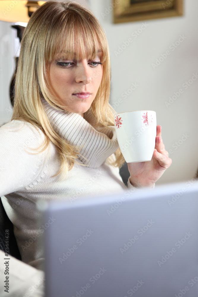 Jeune femme buvant un café devant ordinateur portable Jeune femme buvant un café devant ordinateur portable
