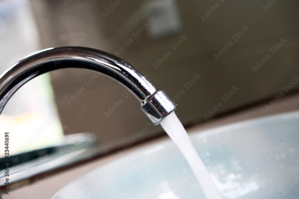 Water dribbling from a leaking faucet on the kitchen sink. . ภาพถ่าย