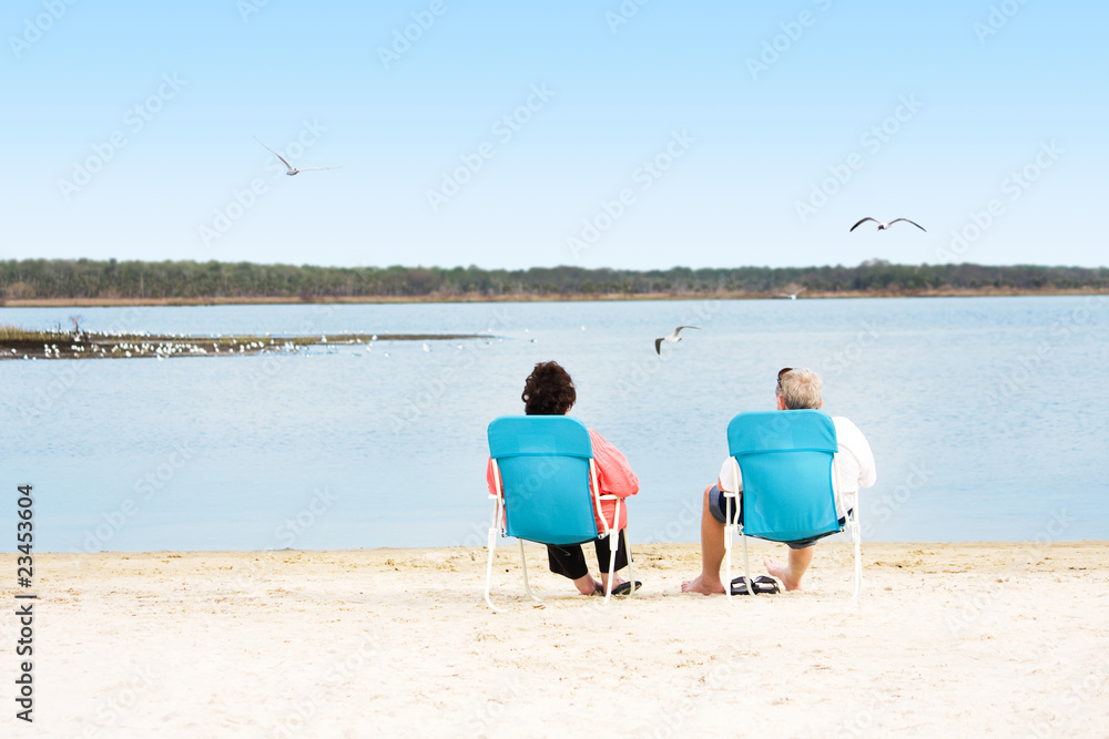 senior couple sitting on chairs near the sea