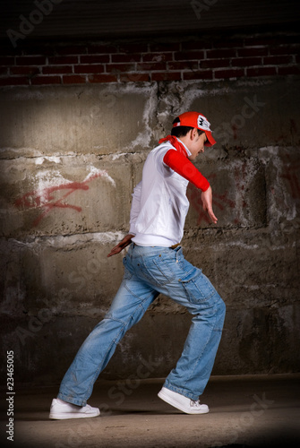 Hip hop boy dancing in modern style over grey brick wall © mr.markin