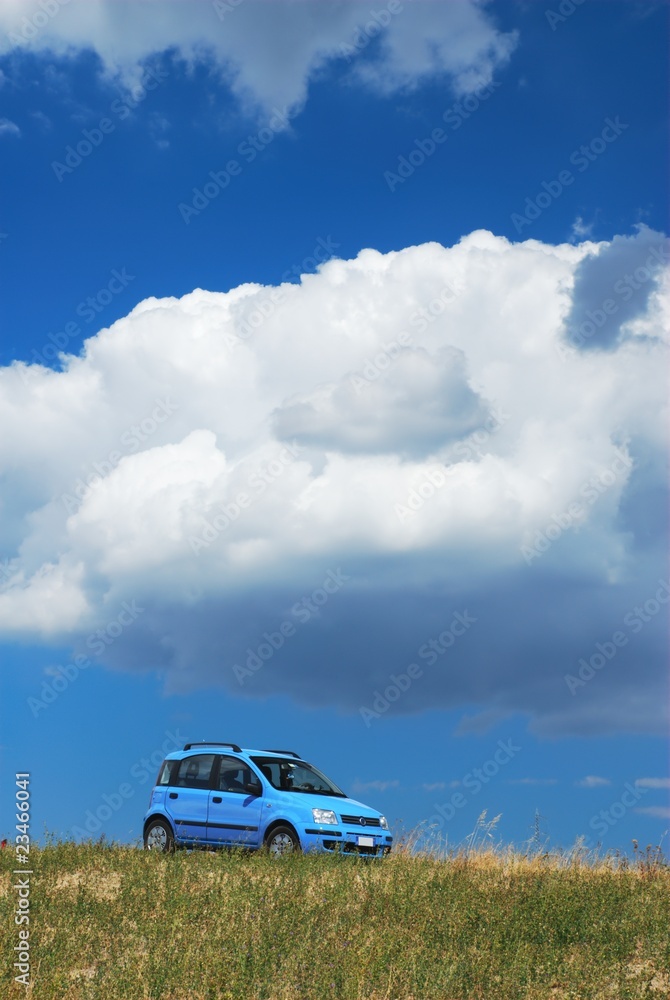 Bright pale blue modern car under white cloud and blue sky