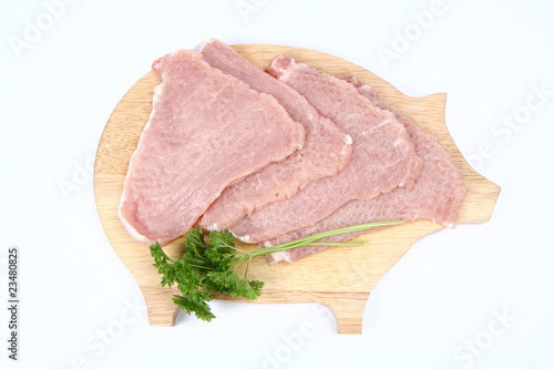 Raw tenderized pork chops on a pig shaped chopping board