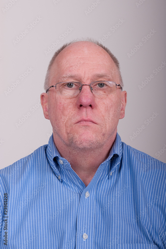 Obraz premium Older Balding Man in Blue Shirt Holding Chin Up Looking Through
