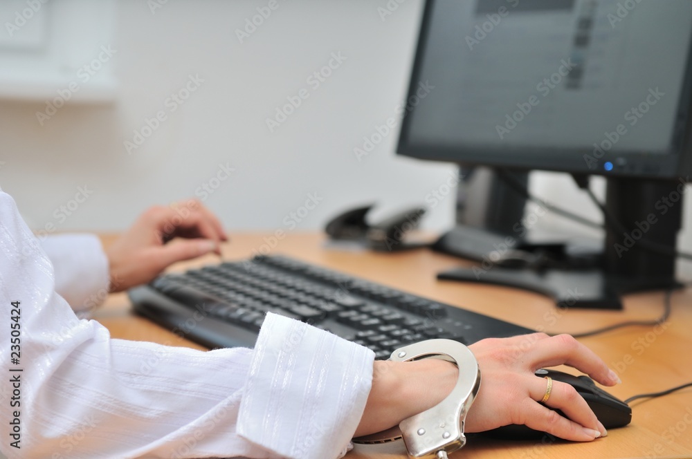 Business person tied with handcuffs to workplace Business person tied with handcuffs to workplace