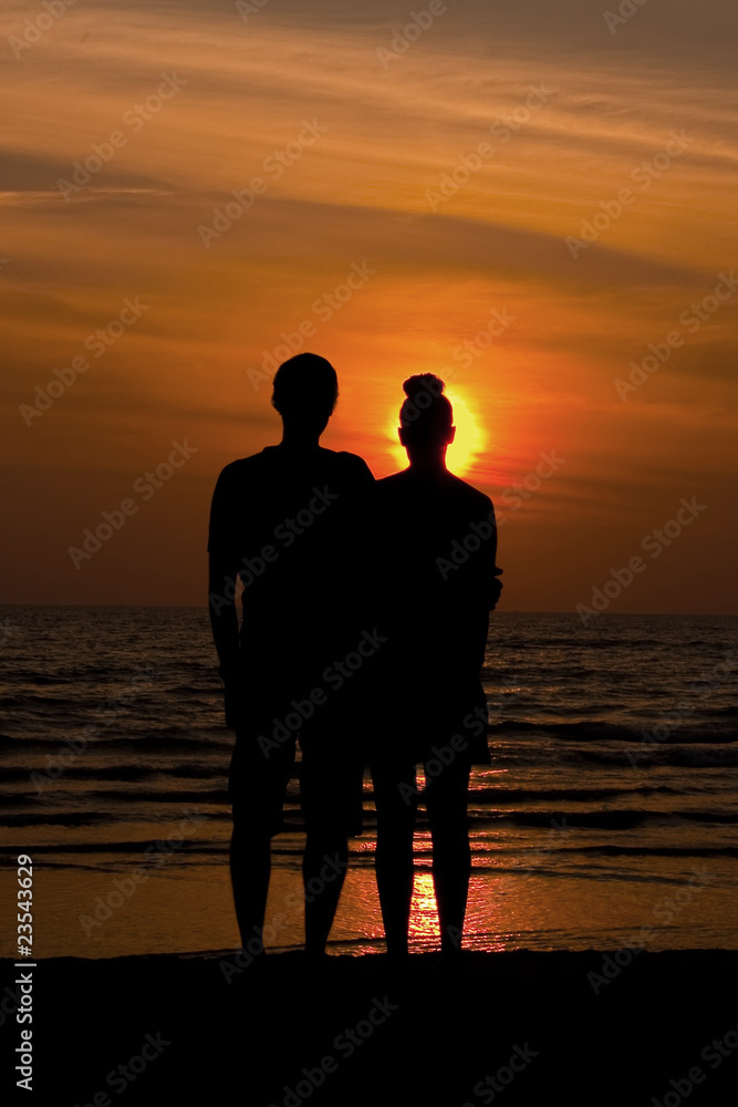 Couple watching the sunset (silhouette) hugging