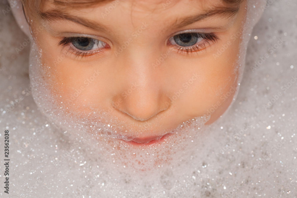 small child taking a bath, head of foam. looks toward