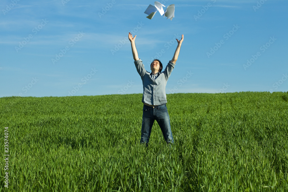 young man throwing a paper in the green field young man throwing a paper in the green field