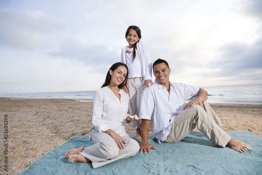 Hispanic family sitting on blanket at beach Hispanic family sitting on blanket at beach