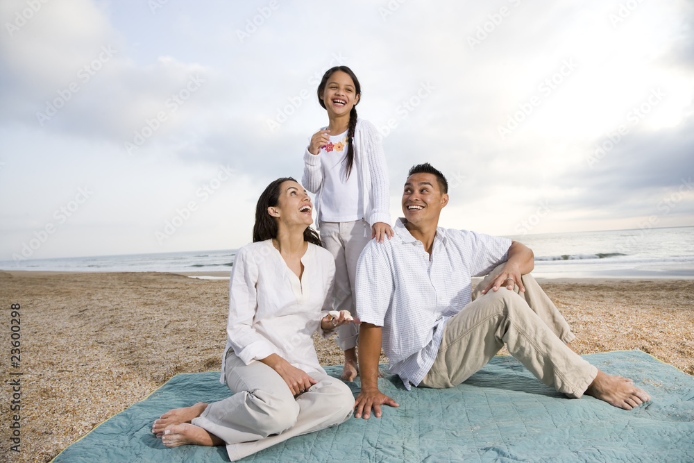 Hispanic family sitting on blanket at beach Hispanic family sitting on blanket at beach