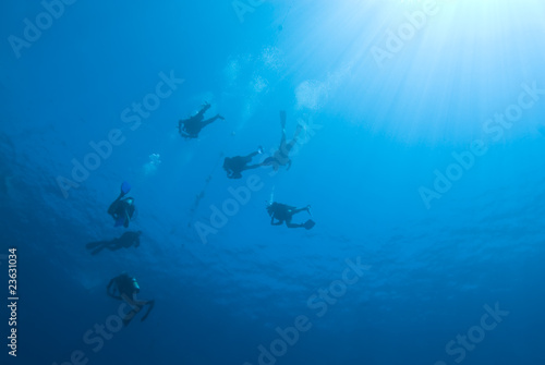 Scuba divers descending into the blue. © caan2gobelow
