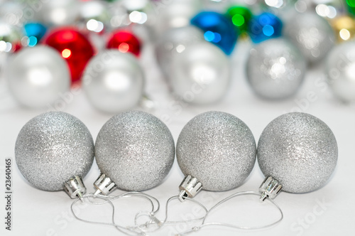 Four grey Christmas balls on foreground and many color balls