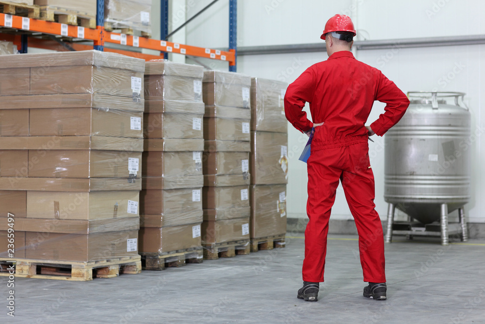 A worker checking inventory stocks at a factory storeroom. A worker checking inventory stocks at a factory storeroom.