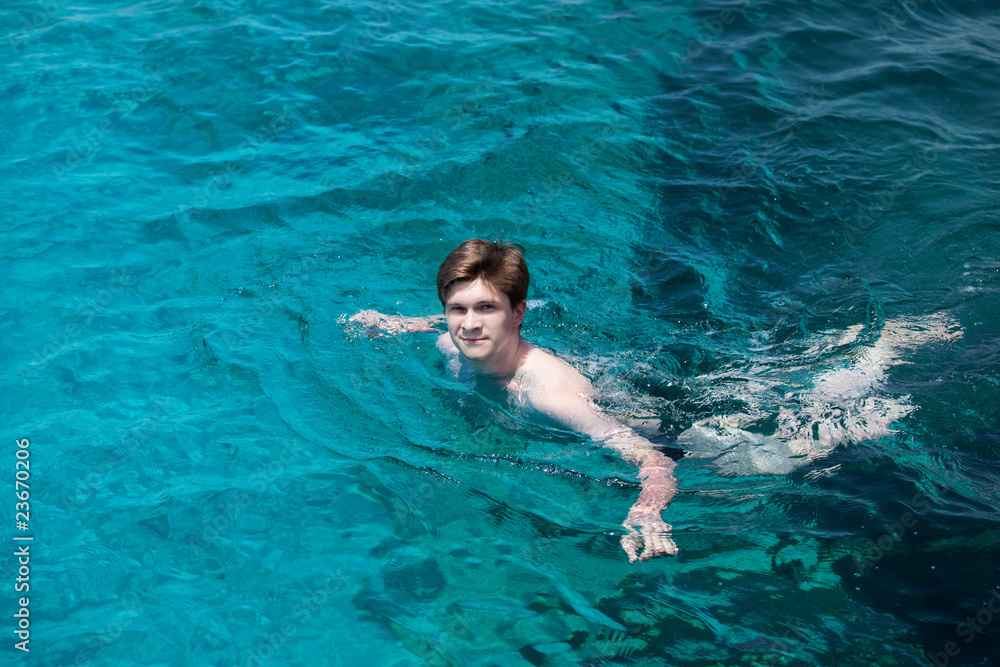 young man swims in the sea.