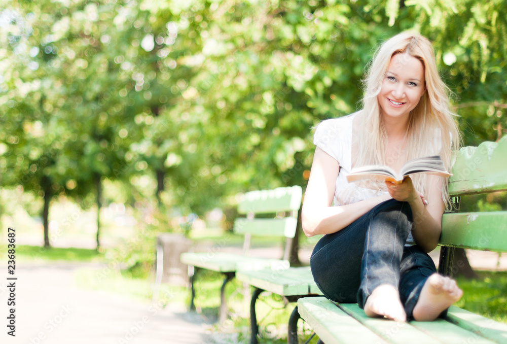 young woman reading book in park