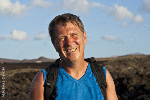 man on walking trail thru volcanic area in Lanzarote looks happy