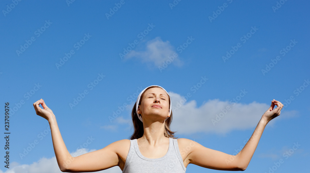 Peaceful woman meditating against a blue sky Peaceful woman meditating against a blue sky