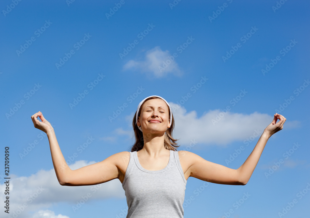 Smiling woman meditating against a blue sky Smiling woman meditating against a blue sky