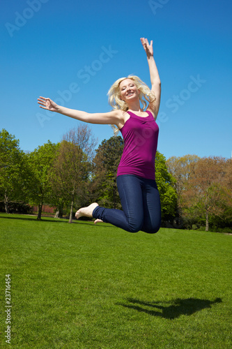 Blonde Frau springt im Park