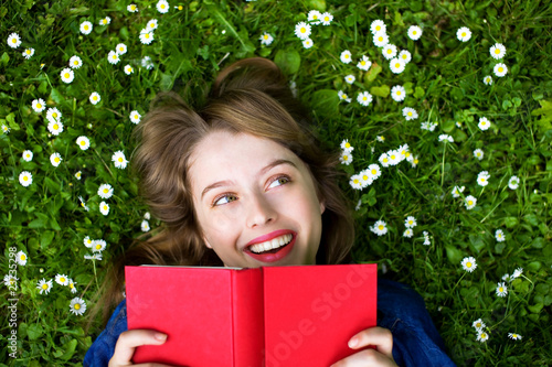 Woman lying on grass, reading book