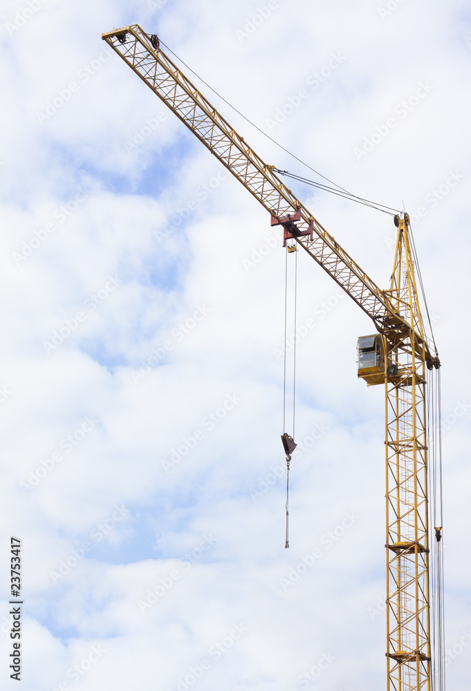 Hoisting crane on a construction site in the cloudy sky