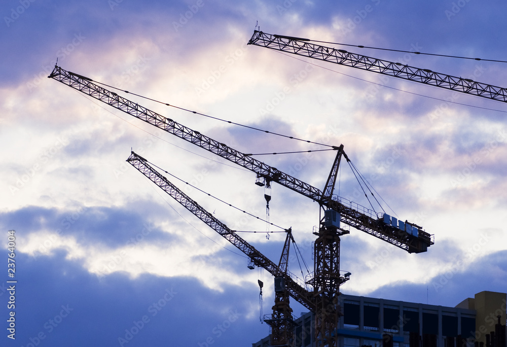Building with elevating crane and clouds on background