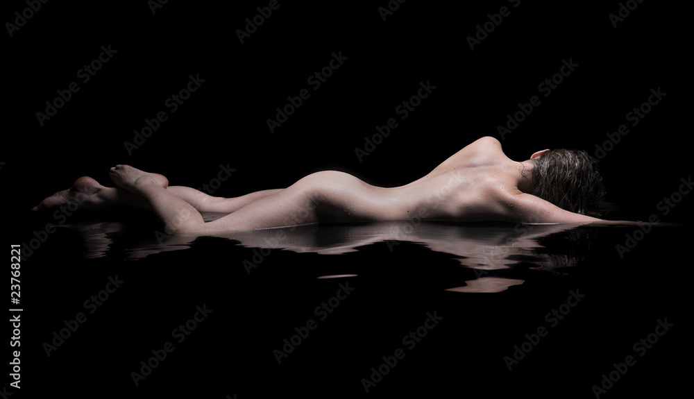 Fototapeta premium Nude woman lies in water, low key