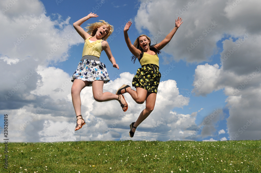 Two girls jumping in grass field Two girls jumping in grass field