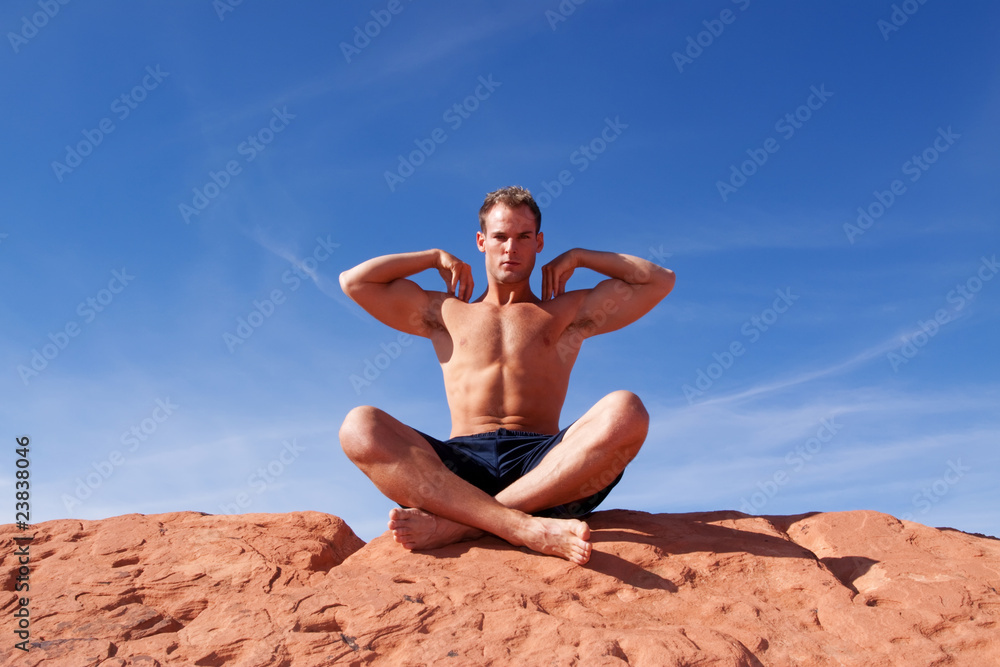 Athletic young man relaxing on red rocks Athletic young man relaxing on red rocks