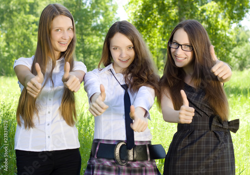 three happy student girl with thumbs-up in the park